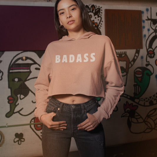 Model wearing peach cropped hoodie with ‘BADASS’ print.