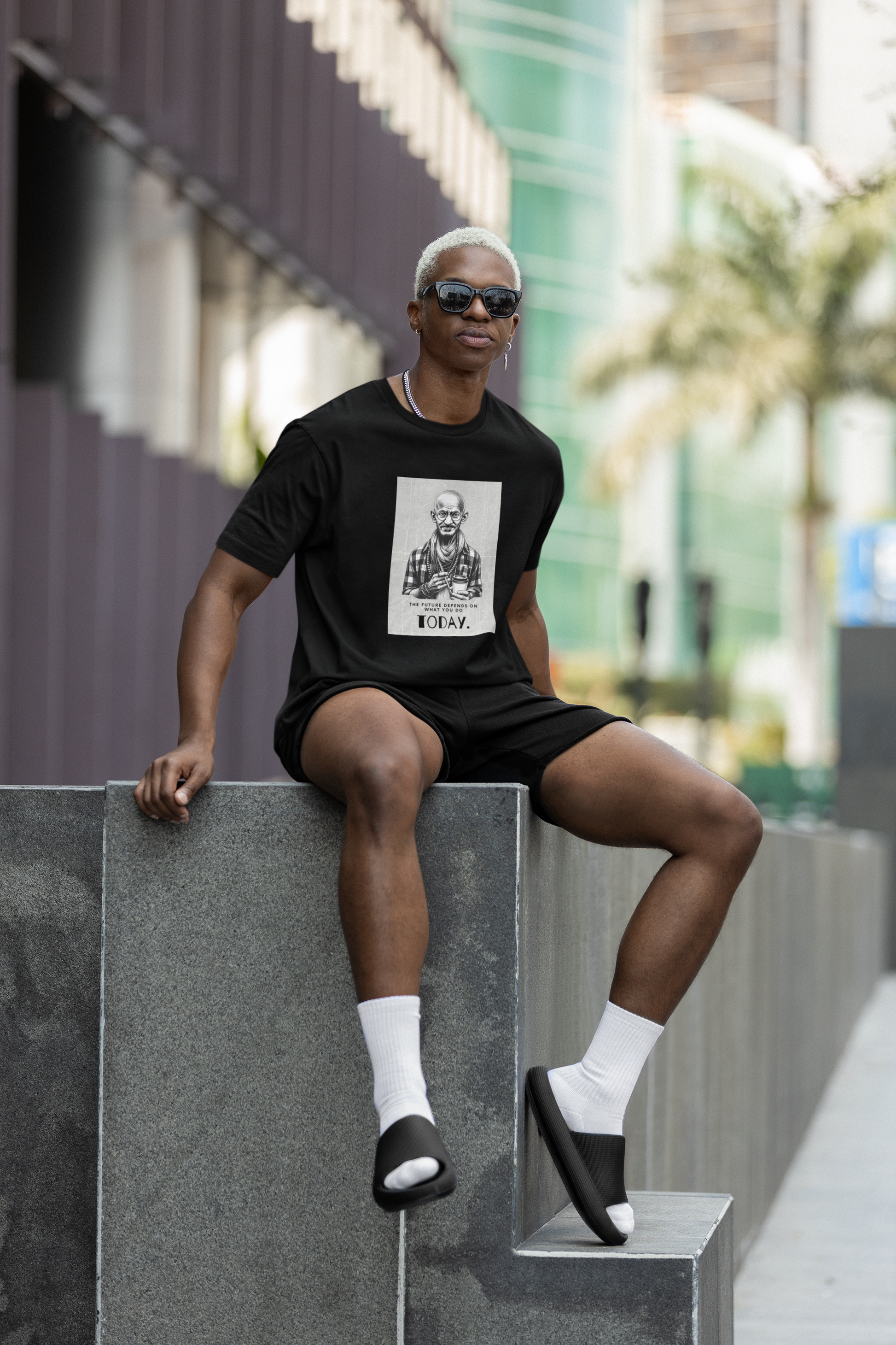 A cool guy in urban jungle sitting wearing Gandhi t-shirt and high white socks