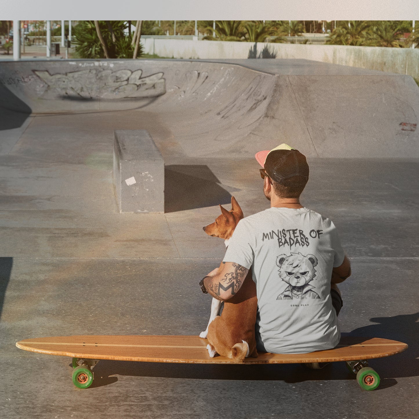 Back view of White tee showing teddy graphic and text.
Man on skateboard with his dog